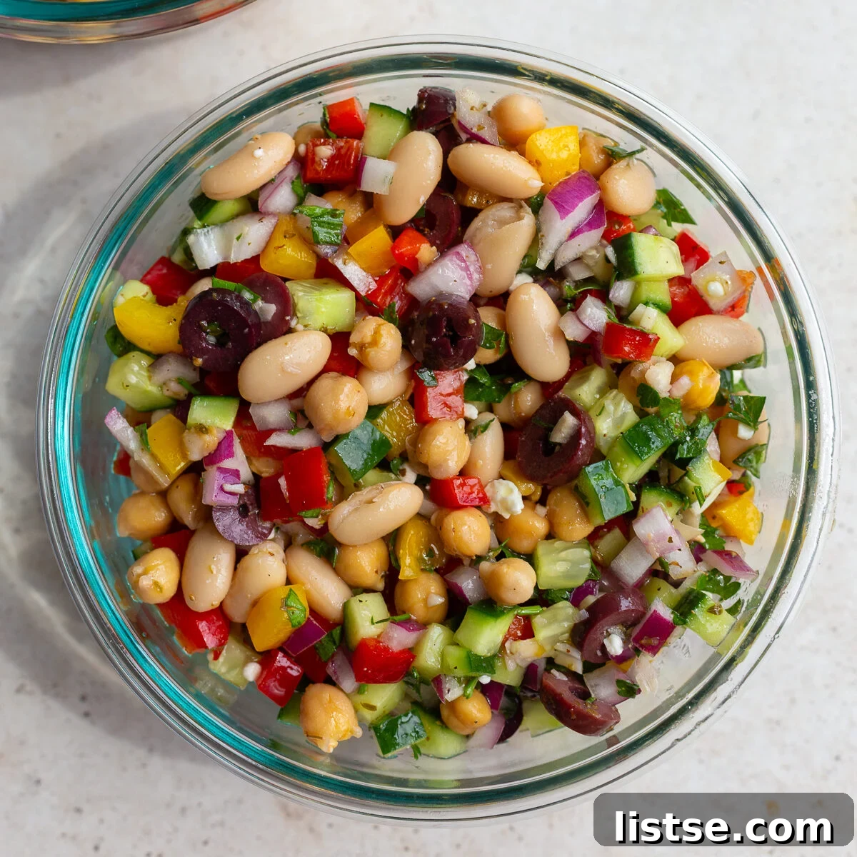 Overhead shot of the Dense Bean Salad in a wide serving bowl, artfully arranged with fresh ingredients and garnished with parsley.