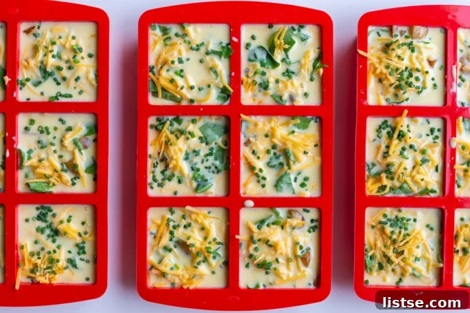 Assembling potato chive egg bites in silicone molds with layers of ingredients.