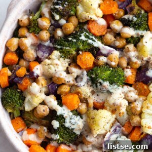 Colorful roasted root vegetables and chickpeas generously coated in a maple dijon dressing, served in a bowl, ready for a healthy vegan dinner or meal prep.