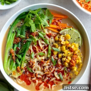 A steaming bowl of rich peanut butter miso ramen, garnished with fresh herbs and chili flakes, promising a flavorful and comforting meal.