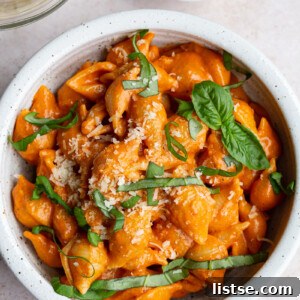 Perfectly cooked pasta shells coated in a rich, creamy, and subtly spicy vodka sauce, generously topped with fresh basil leaves, ready to be enjoyed.