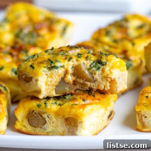 Fluffy and savory potato chive egg bites, resembling Starbucks' famous recipe, stacked artfully with one bite taken, highlighting their creamy texture and fresh chives.