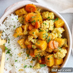 Rich and creamy pumpkin curry served over a bed of white rice in a ceramic bowl, garnished with fresh herbs.