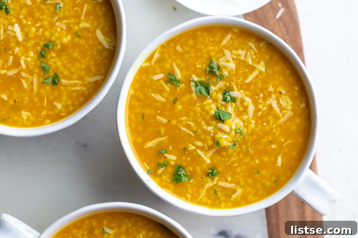 Two bowls of Italian Penicillin soup, garnished with chopped parsley and shredded Parmesan cheese, ready to be served.