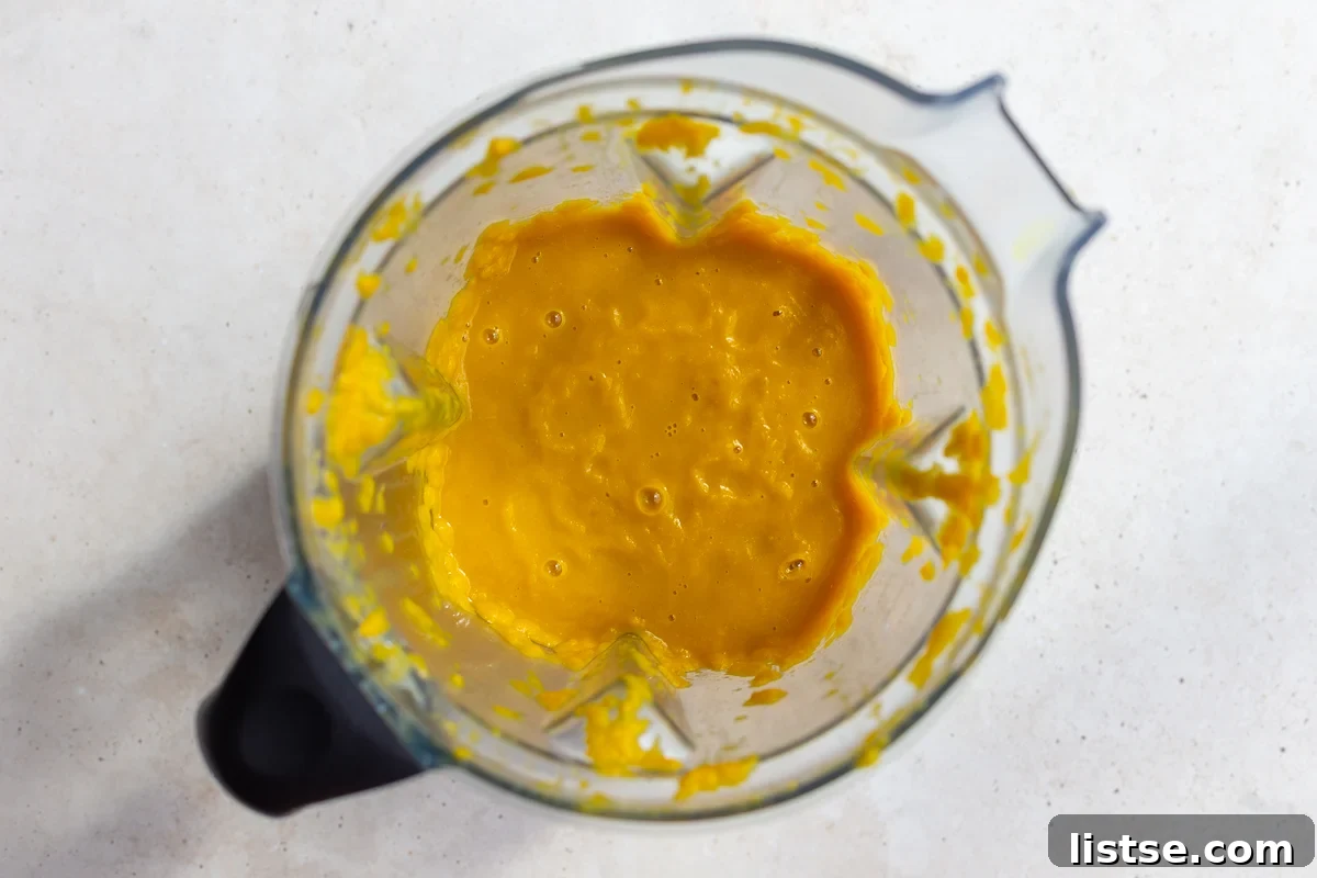 A portion of the cooked vegetable soup base being blended into a creamy texture in a countertop blender.