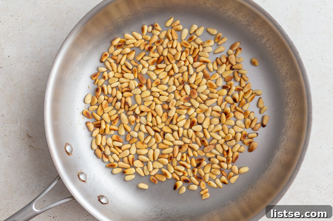 Crafting Perfect Homemade Basil Pesto 6 Pine nuts being toasted in a skillet until golden brown.