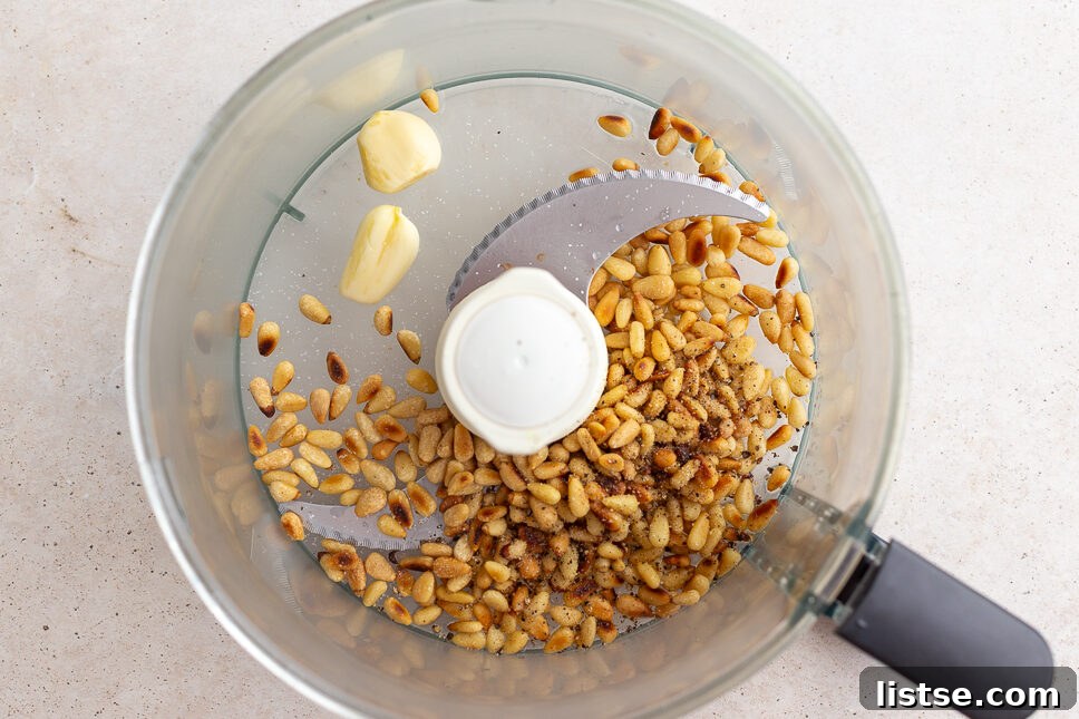 Crafting Perfect Homemade Basil Pesto 7 A food processor containing toasted pine nuts, fresh lemon juice, and garlic cloves.