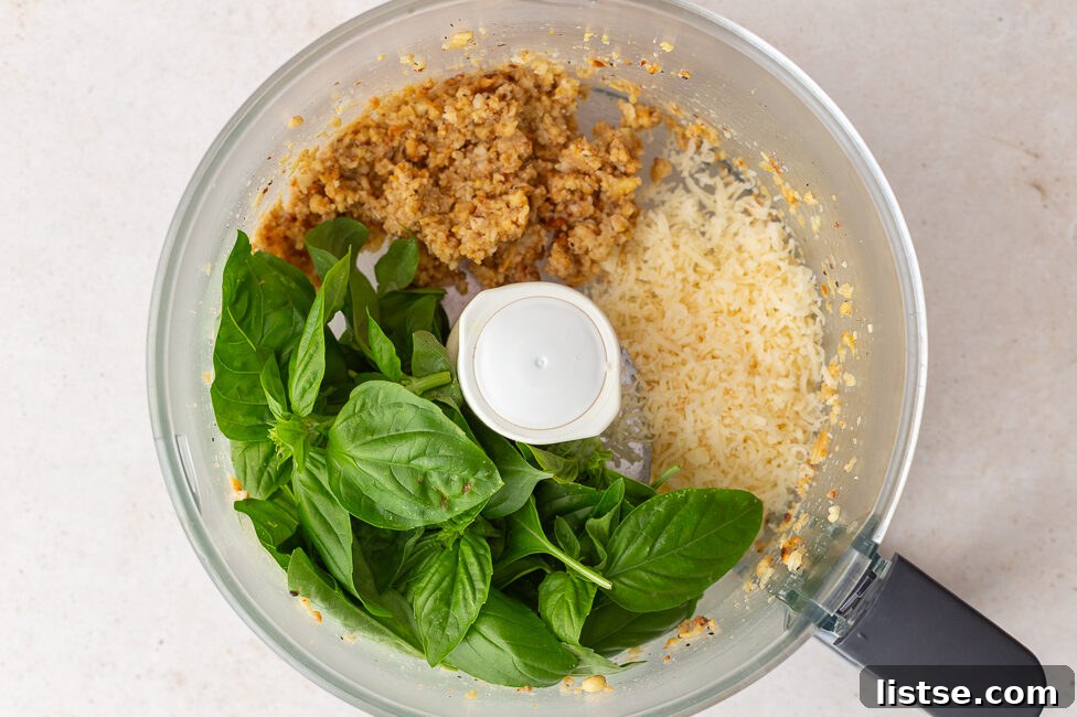 Crafting Perfect Homemade Basil Pesto 8 Fresh basil leaves and grated Parmesan cheese added to the food processor with the blended pine nuts and garlic.
