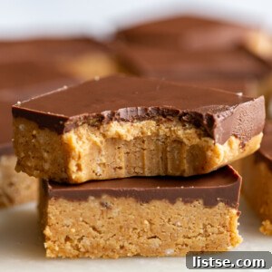 Two decadent chocolate peanut butter bars stacked, with one having a bite taken out, surrounded by more bars, perfect for a no-bake dessert.