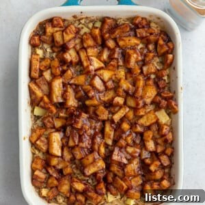 Baked oatmeal topped with warm cinnamon apple chunks in a small teal baking dish, perfect for breakfast.
