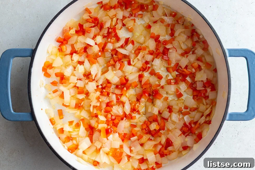 Step 1: Sautéing diced onions and bell peppers in a large skillet with olive oil.