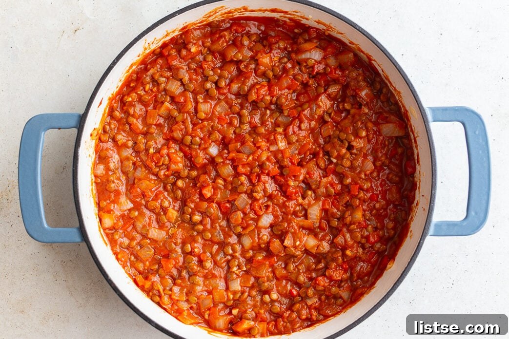 Step 3: Cooked lentils, tomato sauce, ketchup, mustard, and soy sauce combined and simmering in the pan.