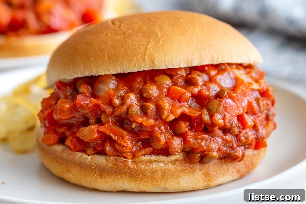 Step 4: Two finished lentil sloppy joes on toasted buns, with fresh garnishes, ready to serve.