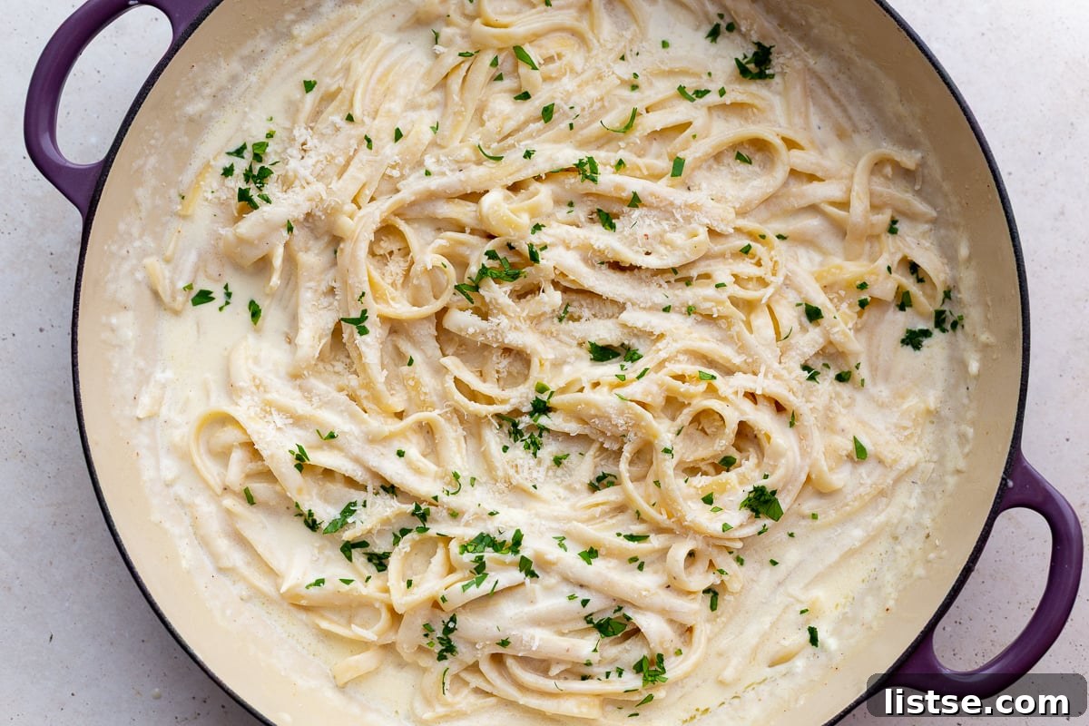 Luscious Homemade Alfredo in Minutes 2 A large skillet filled with homemade fettuccine alfredo sauce, garnished with fresh herbs, ready to be served.