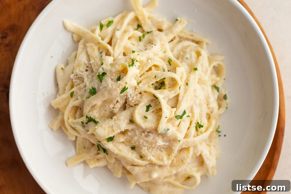 Luscious Homemade Alfredo in Minutes 9 A large bowl of homemade fettuccine alfredo topped with fresh parsley, ready to be enjoyed.