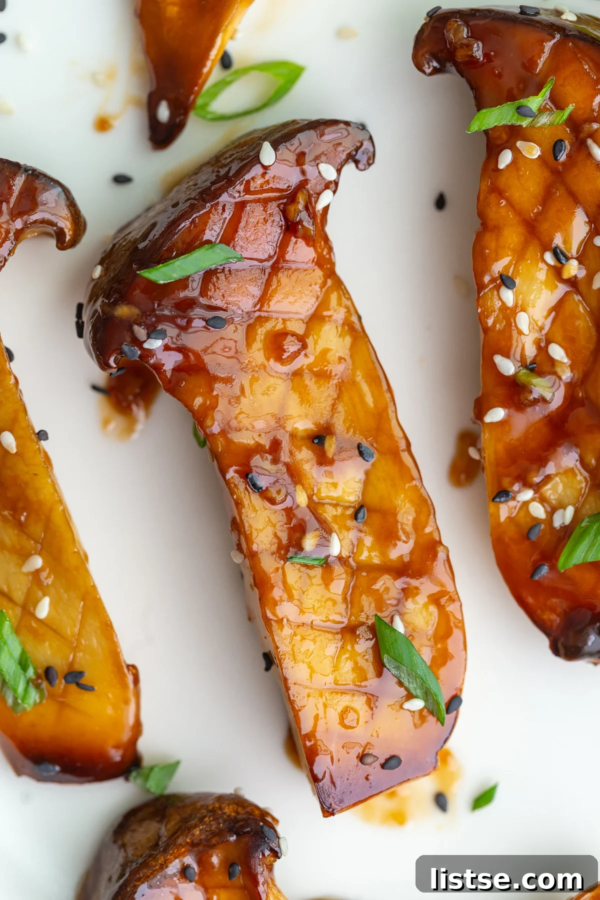 Perfectly cooked sticky teriyaki oyster mushrooms, halved and glistening with sauce, served on a plate.