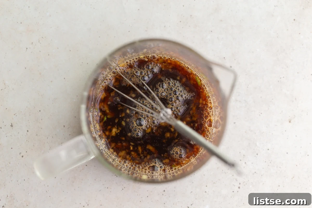 Homemade teriyaki glaze ingredients whisked together in a measuring cup.
