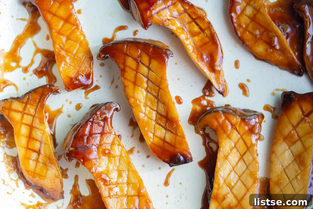 King oyster mushrooms in a skillet coated in a thick, sticky teriyaki sauce.