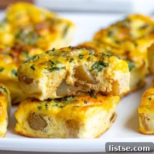 Stacked potato chive egg bites, one with a bite taken out, showcasing their fluffy interior.