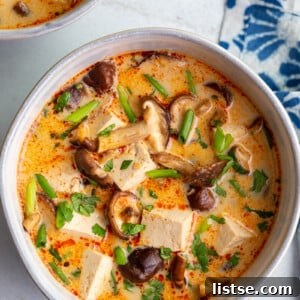 A cozy bowl of Coconut Tofu Soup with mushrooms and fresh herbs.