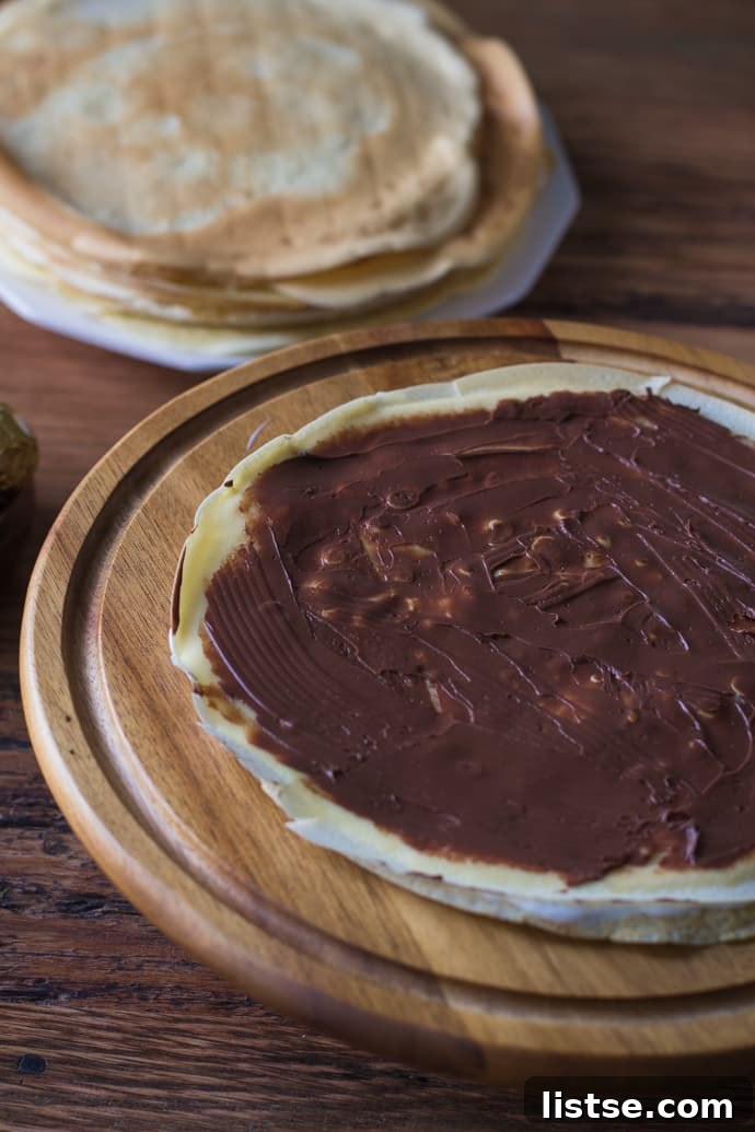 Crepe cake layers building up, showing ganache and whipped cream