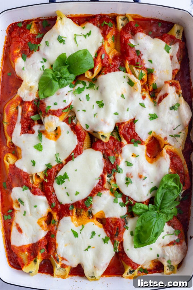 Creamy Spinach Ricotta Stuffed Shells 2 Close-up of baked spinach and ricotta stuffed shells in a casserole dish, topped with melted mozzarella and fresh basil.