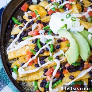 A vibrant platter of Nacho Fries with melted cheese, fresh avocado, and a sriracha sour cream drizzle.