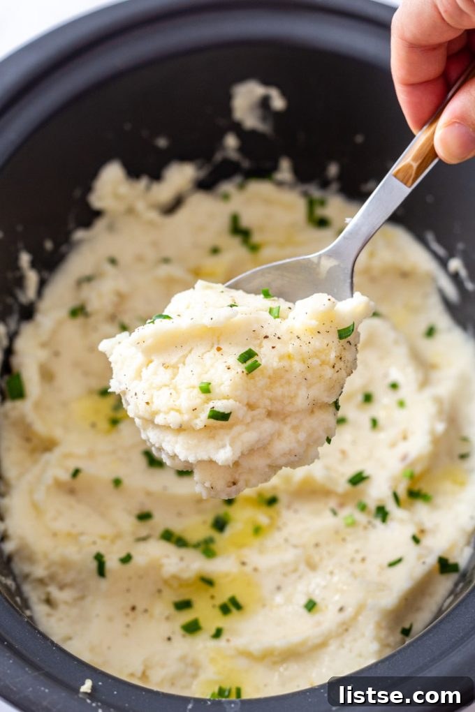 Velvety Slow Cooker Mashed Potatoes 3 A large serving spoon dishing out fluffy crock pot mashed potatoes from a slow cooker