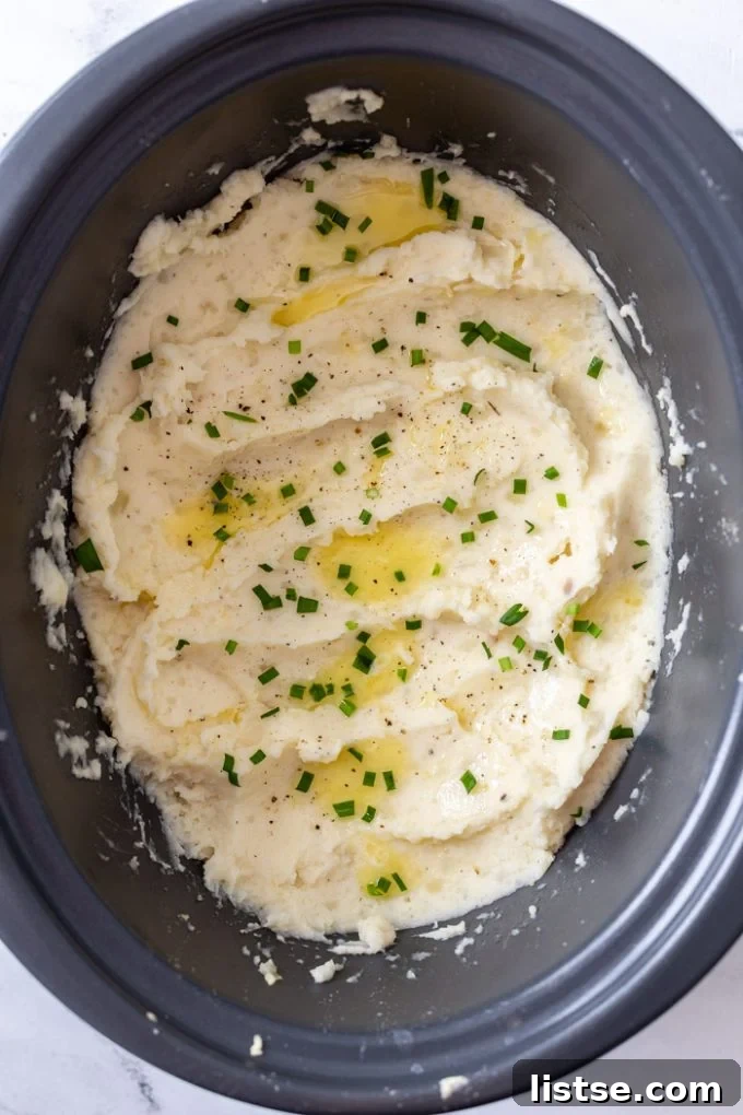 Velvety Slow Cooker Mashed Potatoes 6 Fluffy crock pot mashed potatoes topped with melted butter and fresh green herbs in a serving bowl