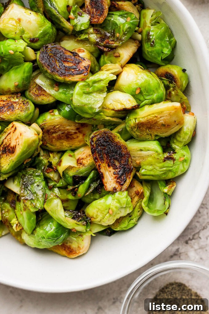 Quick and Crispy Sautéed Brussels Sprouts 2 Perfectly sautéed Brussels sprouts, glistening with garlic-infused olive oil and butter, served in an elegant white bowl, ready to be enjoyed as a gourmet side dish.