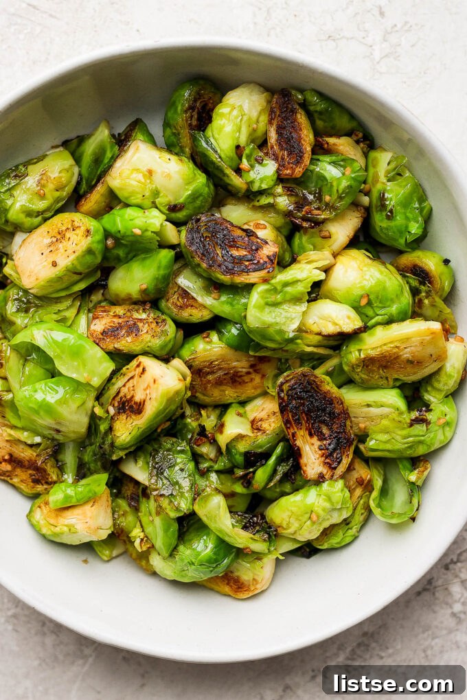 Quick and Crispy Sautéed Brussels Sprouts 3 Close-up shot of crispy, golden-brown Brussels sprouts piled high in a large white serving bowl, showcasing their irresistible texture.