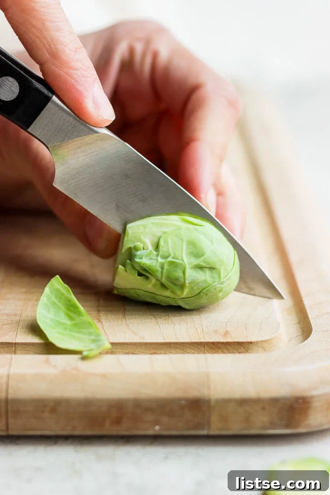 Quick and Crispy Sautéed Brussels Sprouts 5 A Brussels sprout neatly sliced in half lengthwise on a cutting board, revealing its inner layers and prepared for pan-frying.