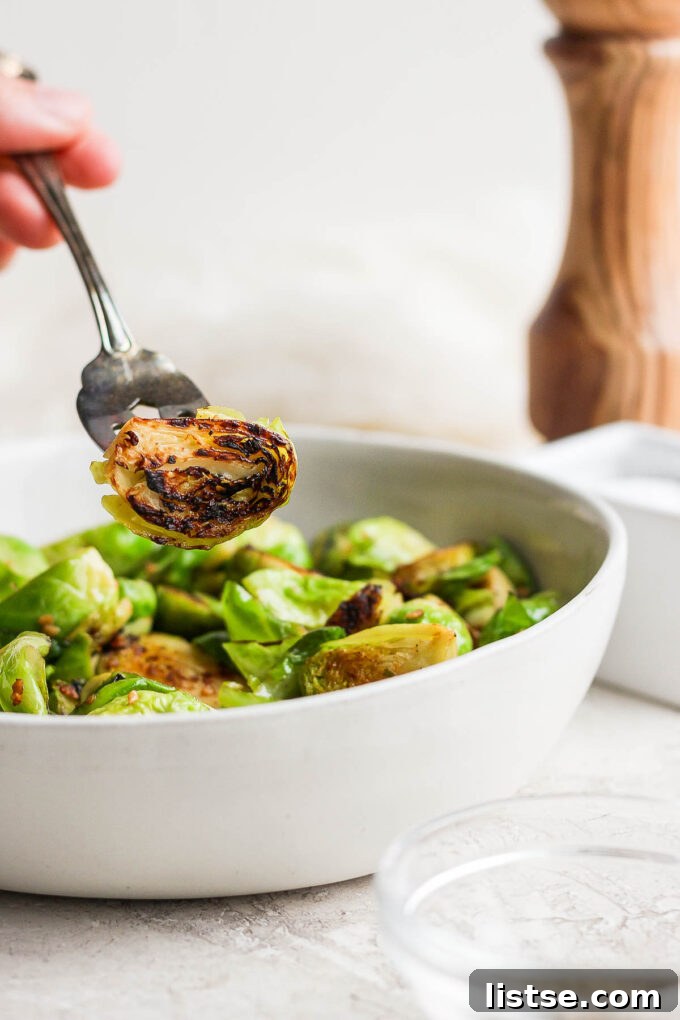 Quick and Crispy Sautéed Brussels Sprouts 10 A fork piercing a perfectly browned and crispy Brussels sprout, highlighting its inviting texture and delicious appearance.