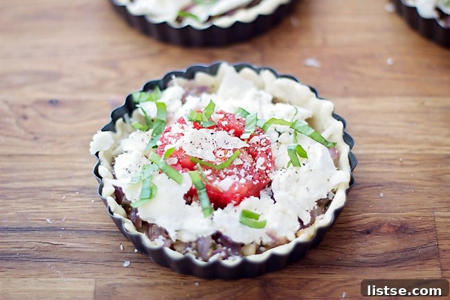 Goat Cheese and Thyme Tarts Unbaked goat cheese tarts with tomato, basil, and Parmesan on a baking sheet