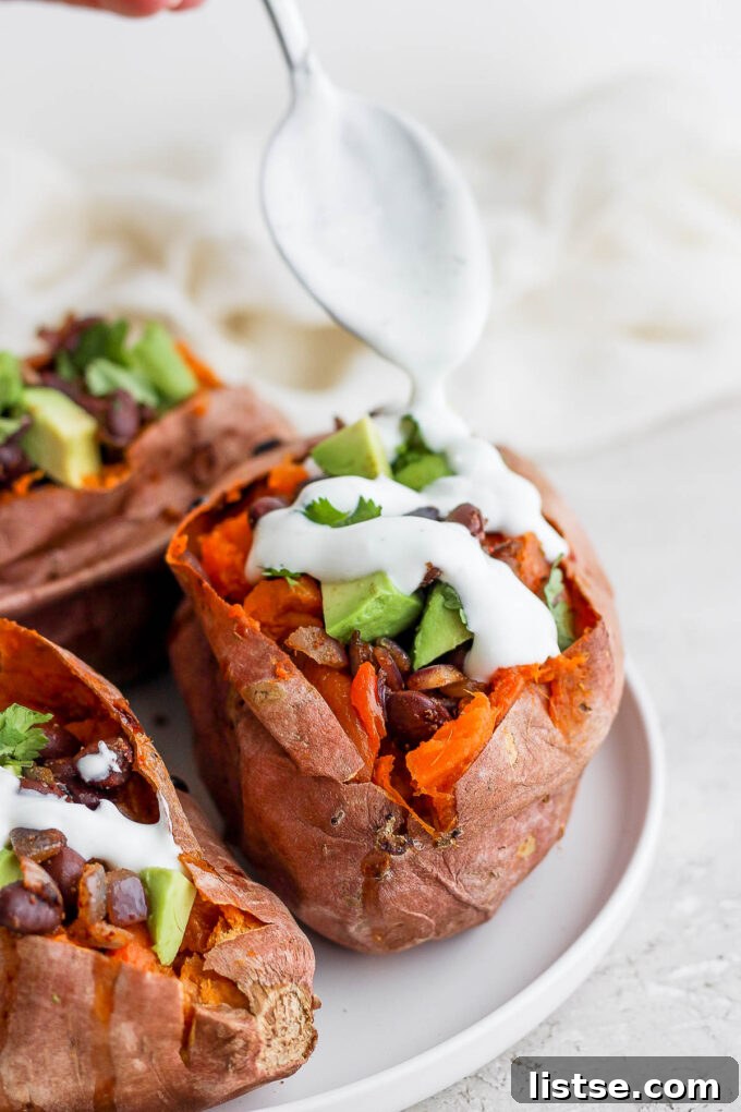 A beautifully presented black bean stuffed sweet potato, adorned with fresh avocado, cilantro, and a creamy vegan dressing, ready to be enjoyed.