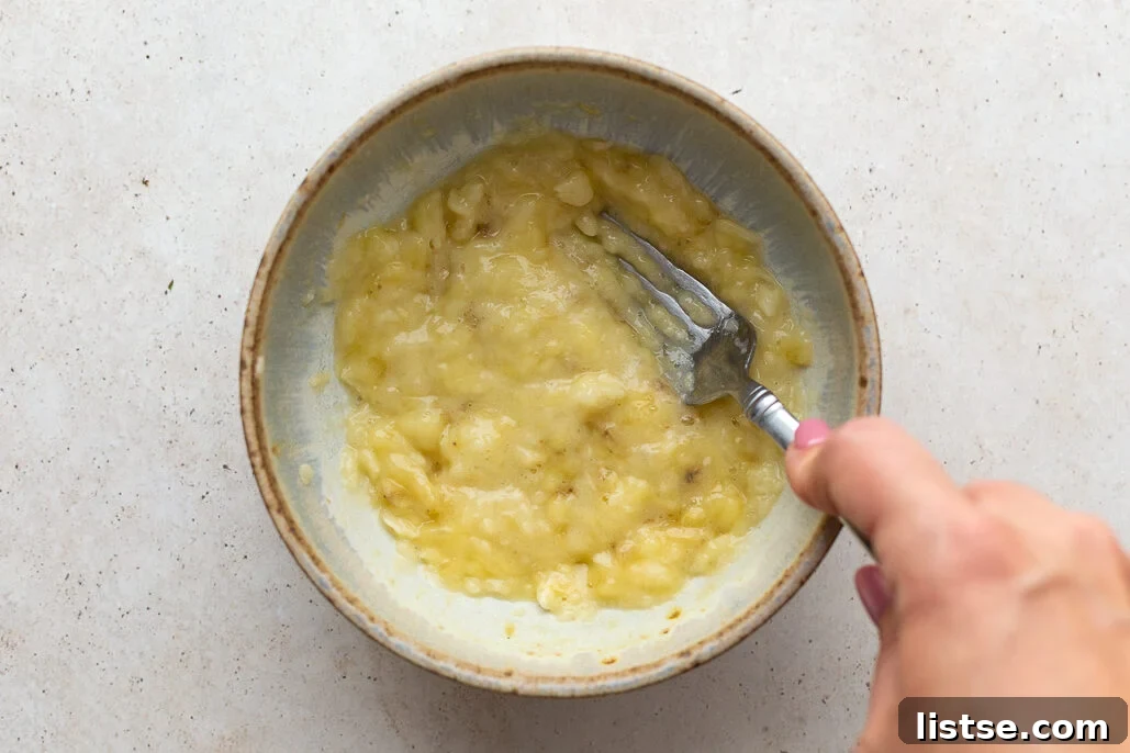 Plant-Powered Chocolate Chip Delights 6 Ripe banana being mashed in a bowl with a fork for muffins