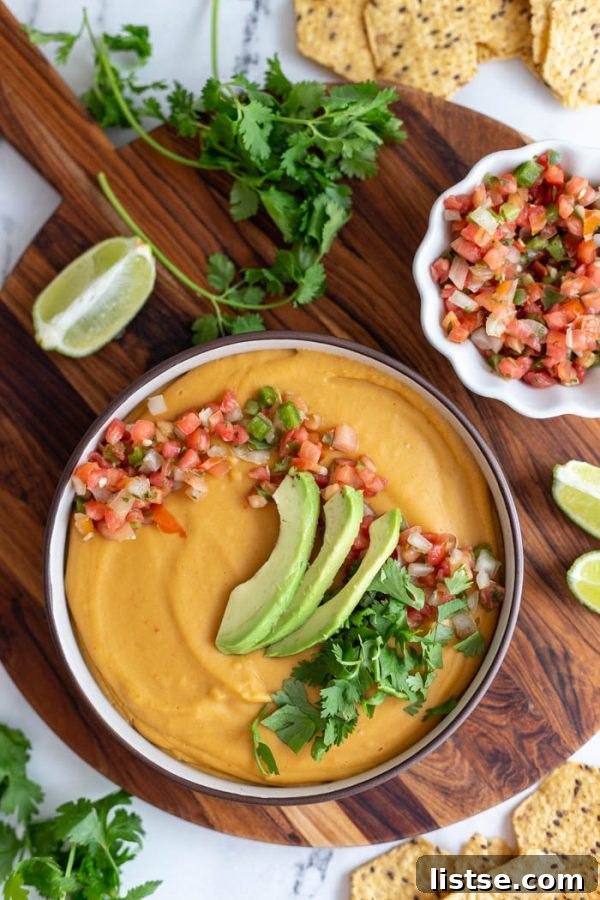 Creamy vegan nacho cheese sauce served on a rustic wooden board, ready for dipping.