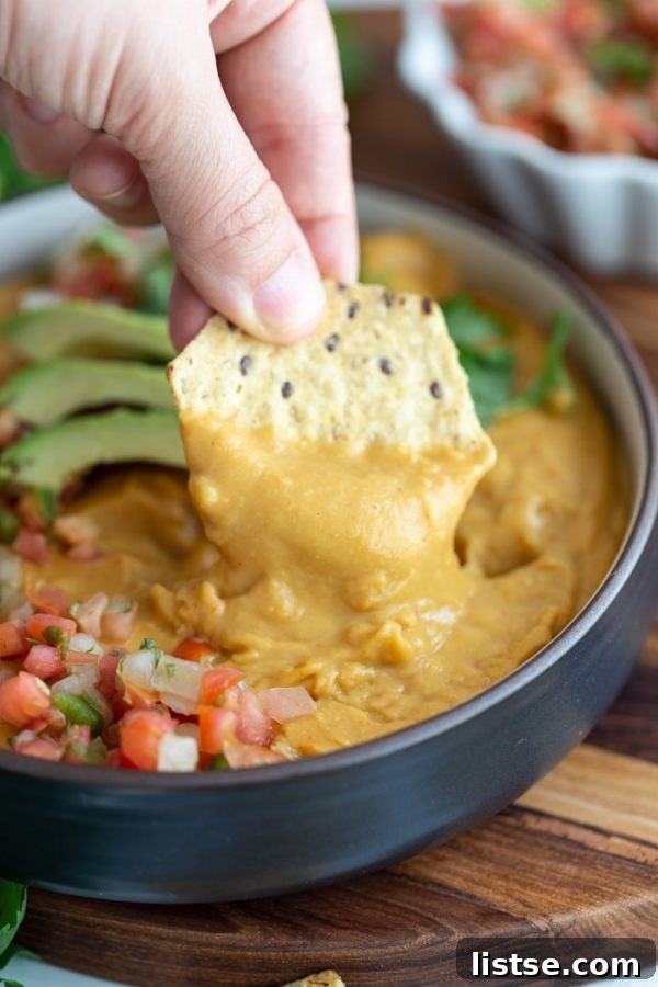 A crisp tortilla chip generously loaded with rich, creamy vegan nacho cheese sauce.