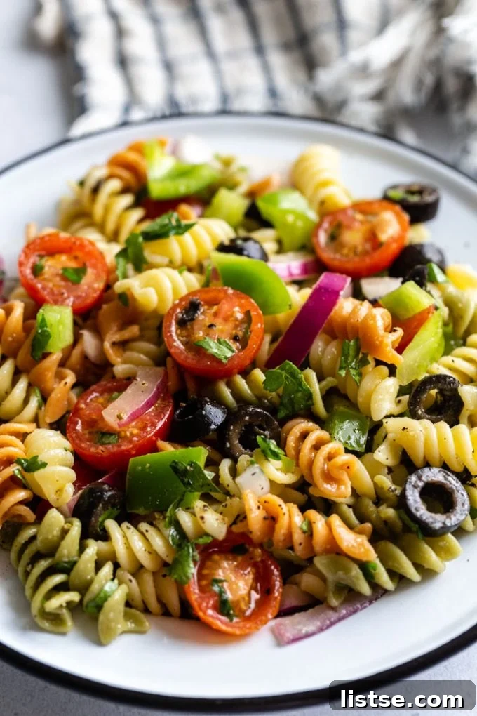 Close up shot of vegan pasta salad with tri-color pasta spirals and fresh vegetables, showcasing the vibrant ingredients.