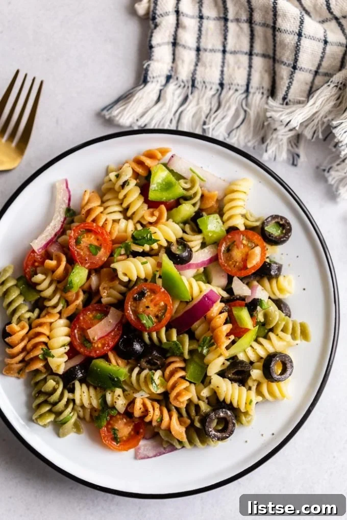 Overhead shot of vegan pasta salad with tri-color pasta spirals and fresh vegetables in a large serving bowl.