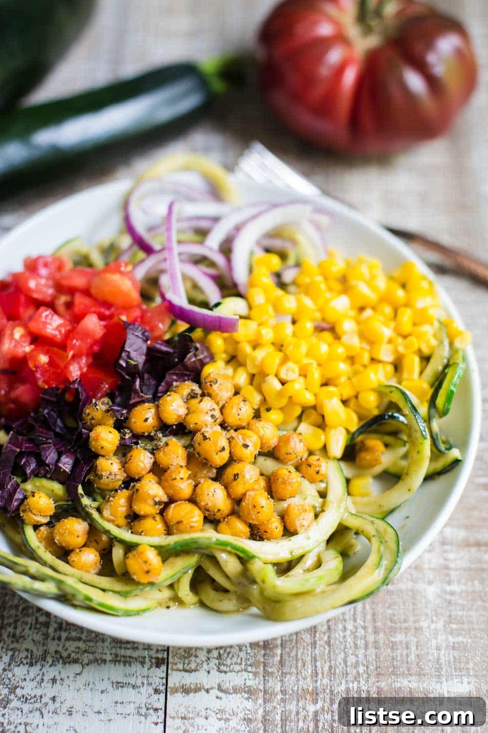Delicious Summer Harvest Zoodles with creamy avocado sauce and an array of fresh vegetables and crispy chickpeas