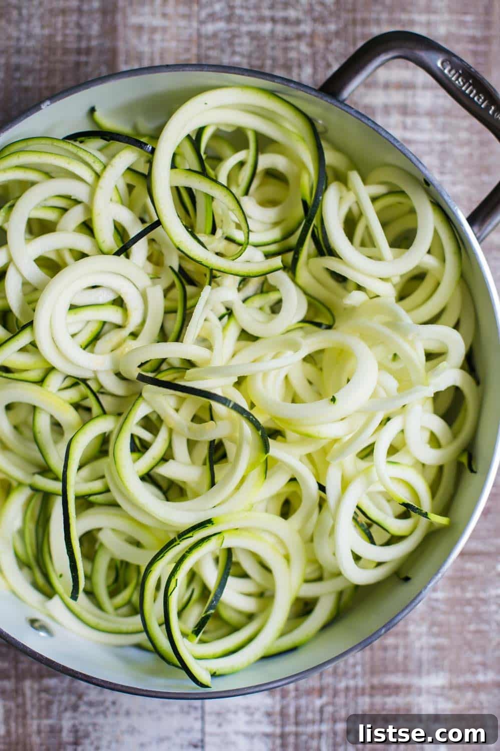 Close-up of vibrant zucchini noodles tossed with creamy avocado sauce and topped with colorful summer vegetables and chickpeas