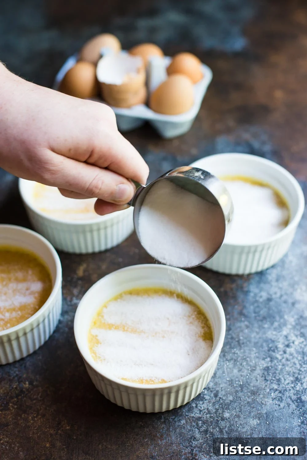 Preparing Dairy-Free Crème Brûlée for torching by sprinkling sugar on top.