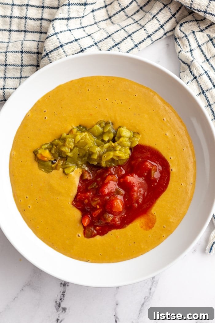 large wooden bowl filled with vegan salsa con queso and topped with salsa and green chiles.