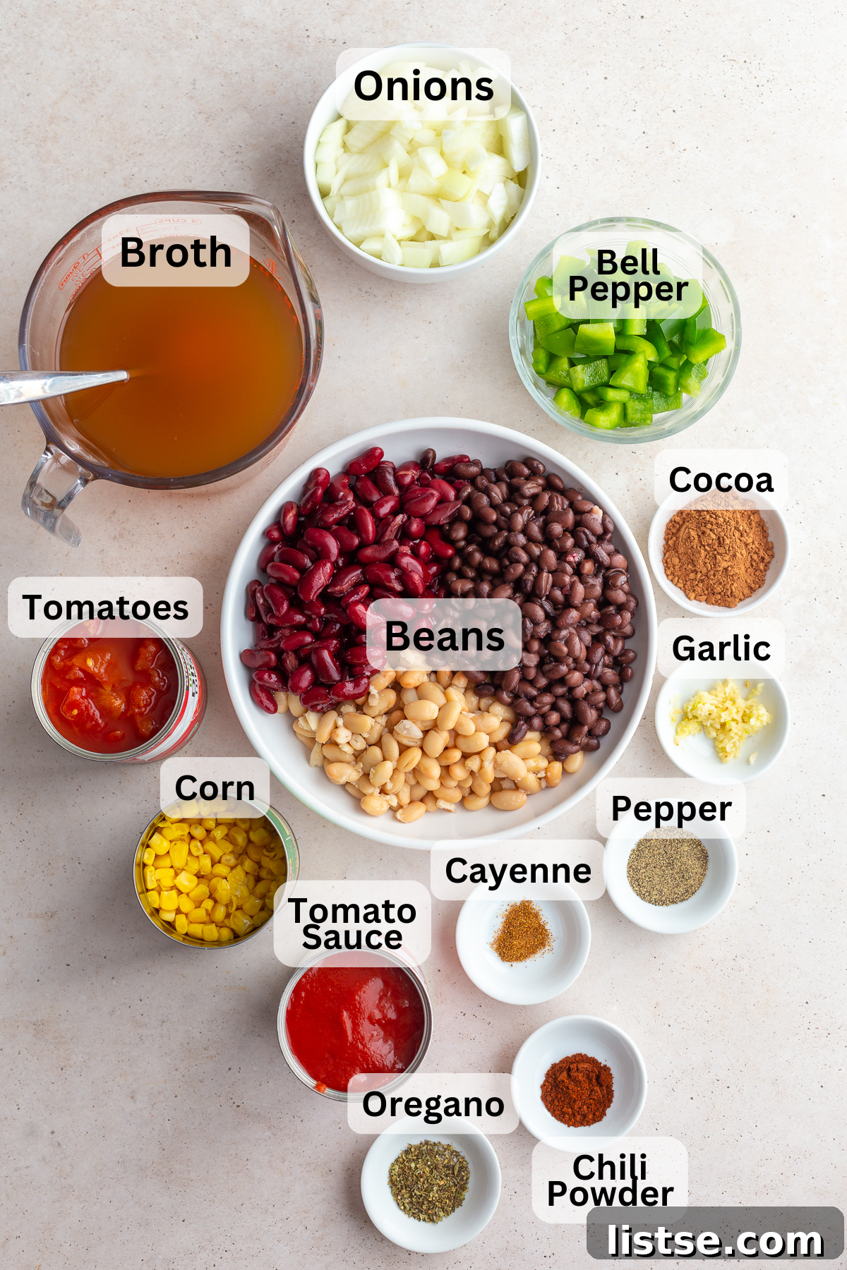 Ultimate Plant-Based Chili 4 A colorful array of fresh ingredients laid out for vegetarian chili, including various beans, juicy tomatoes, sweet corn, onions, bell peppers, and savory vegetable broth.