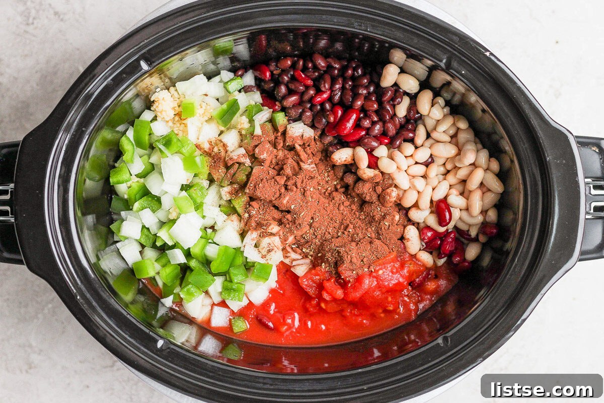 Ultimate Plant-Based Chili 9 All the wholesome vegan chili ingredients, including various beans, tomatoes, corn, and spices, are carefully placed into a slow cooker, ready for a long, slow simmer.