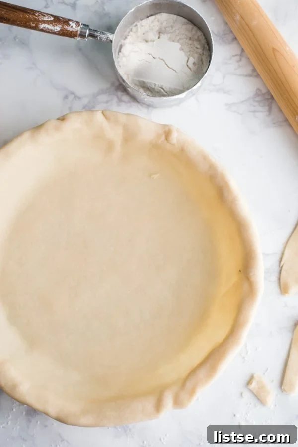 Close-up of a perfectly crimped coconut oil vegan pie crust edge in a white pie dish, ready for baking