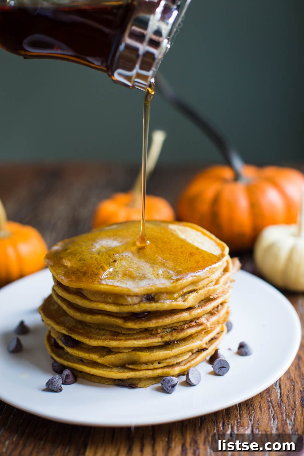 A high stack of golden-brown Pumpkin Spice Chocolate Chip Vegan Pancakes, ready to be served.