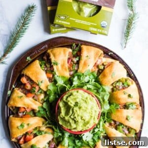Crispy golden Holiday Wreath Taco Ring with a central bowl of guacamole, garnished with cilantro, ready for serving.