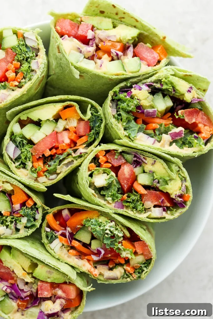 A freshly prepared veggie wrap, showcasing a cross-section of colorful hummus and crisp, fresh vegetables, ready to be enjoyed as a healthy meal.